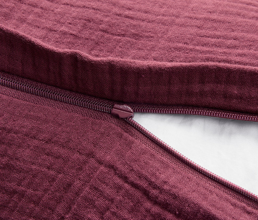 Gros plan sur une texture de tissu bordeaux avec une fermeture éclair ouverte.