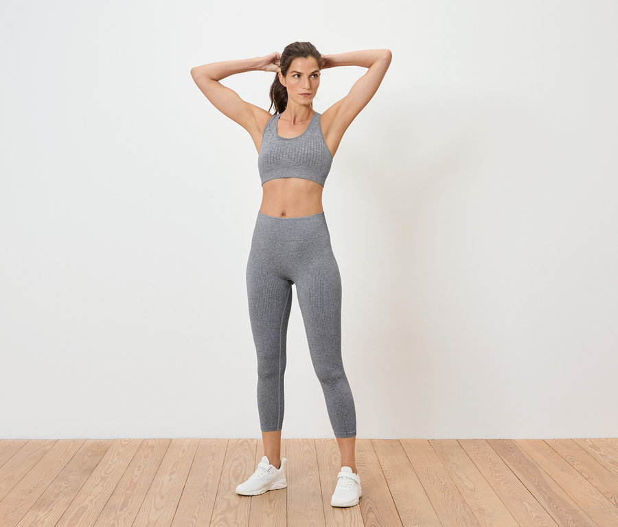 Femme posant en soutien-gorge de sport et leggings gris.