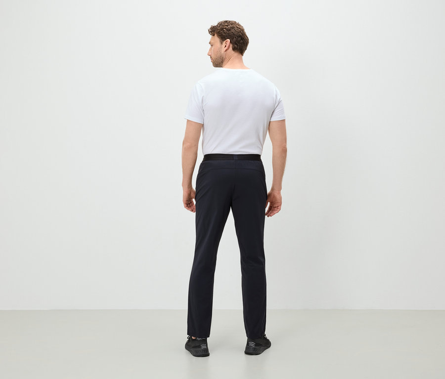 Un homme vu de dos portant un t-shirt blanc, un pantalon noir et des chaussures noires.