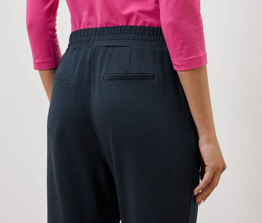 Gros plan du dos d'une femme portant un pantalon bleu marine et un haut rose.