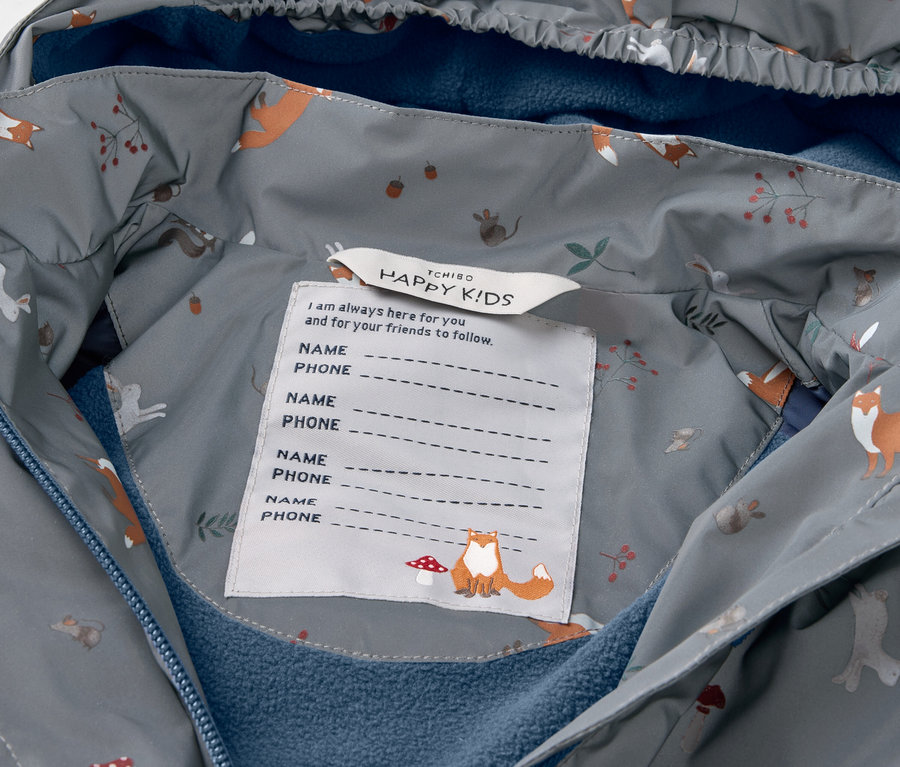 Détail d'une veste de pluie thermique pour enfant avec des éléments réfléchissants.