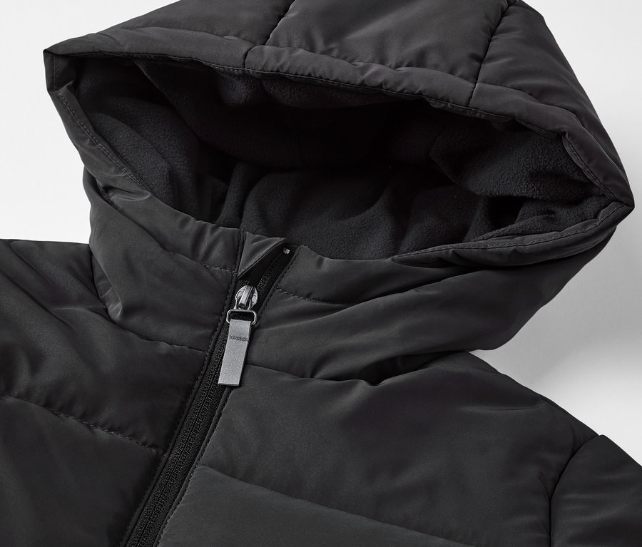 Gros plan sur une veste matelassée noire pour enfant avec des éléments réfléchissants.