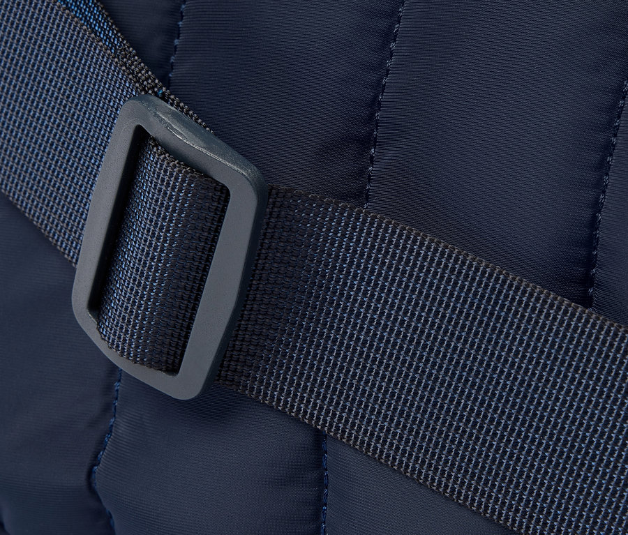Gros plan d'un sac matelassé bleu marine avec une bandoulière et une boucle bleues.
