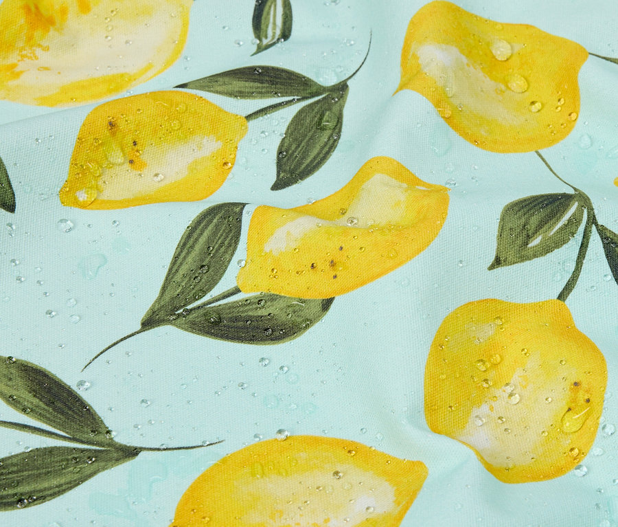 Gros plan d'un tissu bleu clair avec un motif de citrons jaunes et de feuilles vertes avec des gouttes d'eau.