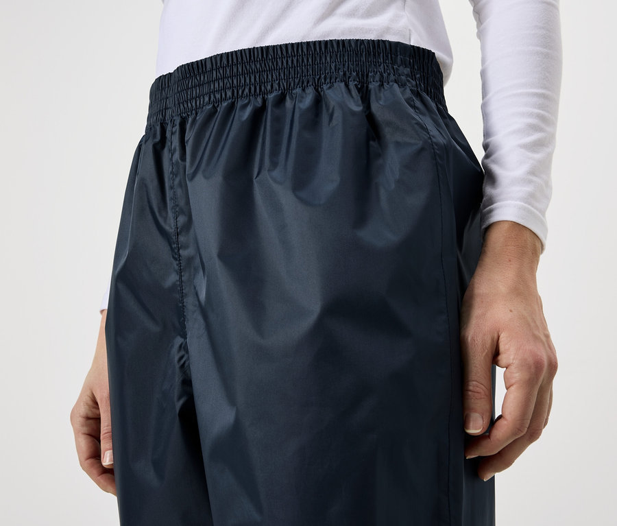 Une personne porte un pantalon de pluie bleu marine avec une taille élastique.