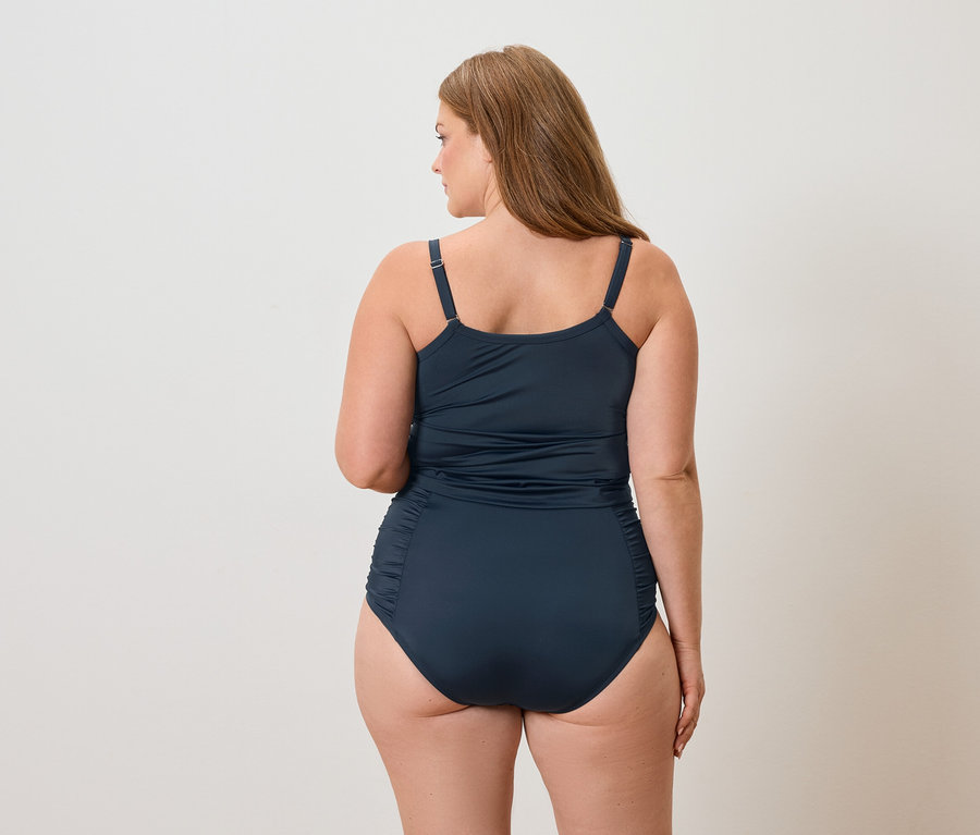 Vue arrière d'une femme aux longs cheveux bruns portant un maillot de bain bleu marine.