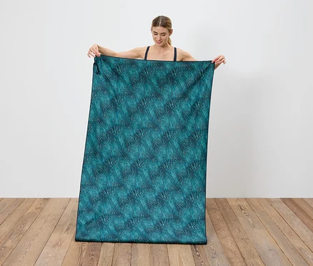 Femme tenant un tissu bleu-vert avec un motif abstrait.