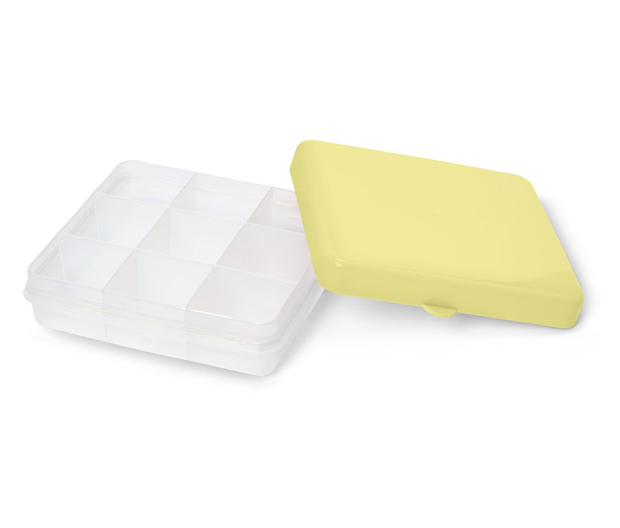 Une boîte de rangement transparente avec des compartiments et un couvercle jaune à côté.