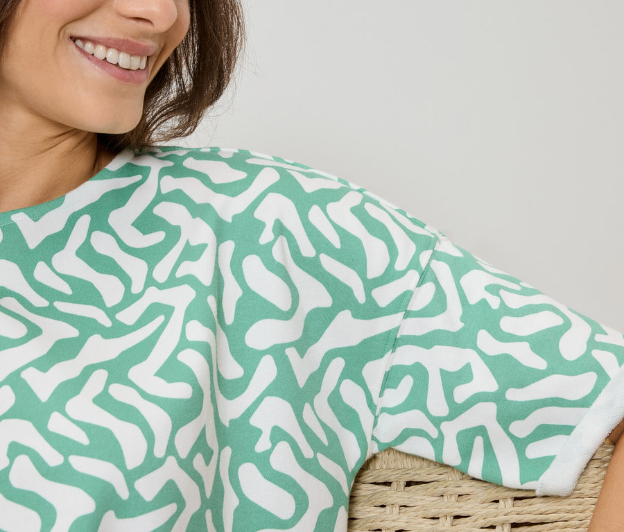 Femme portant un haut à motif vert et blanc.