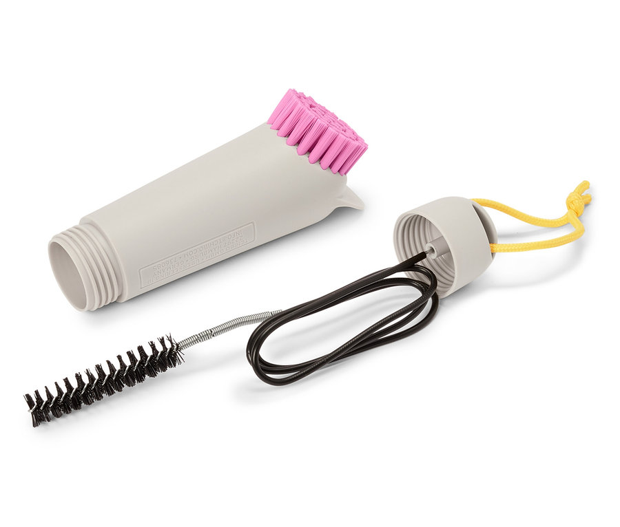 Brosse de nettoyage grise avec poils roses, petite brosse et ruban jaune sur fond blanc.