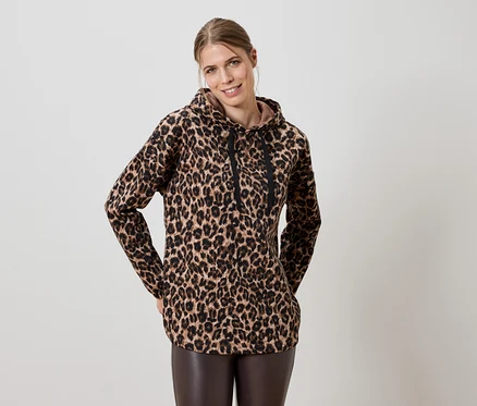 Femme portant un sweat à capuche marron à imprimé léopard et un legging en cuir marron.