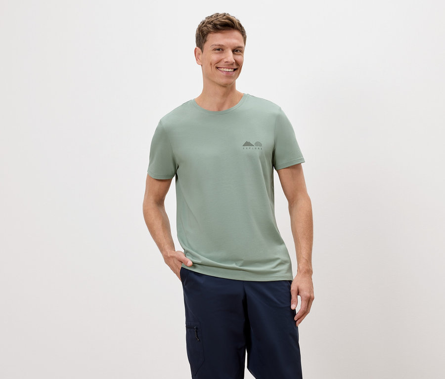 Homme portant un t-shirt vert clair et un short bleu sur un fond blanc.