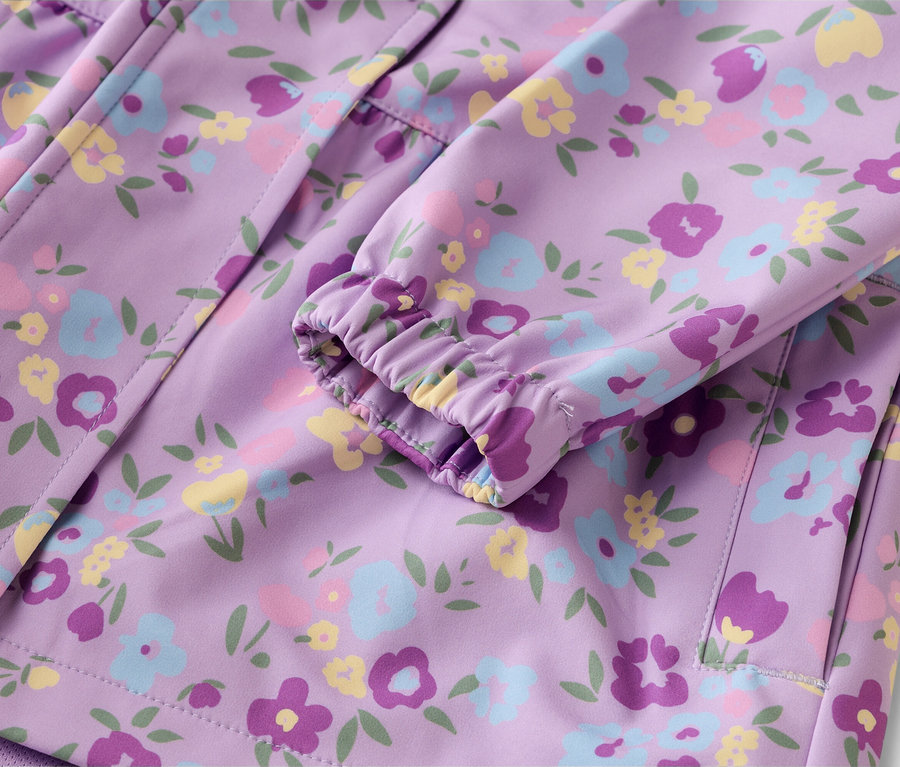 Gros plan d'une veste violette à motifs floraux, avec la manche et la poche visibles.