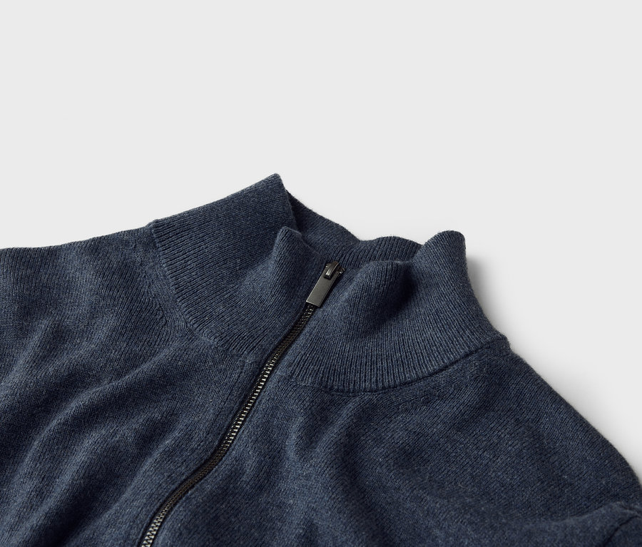 Gros plan d'un pull en tricot bleu marine avec fermeture éclair et col montant.