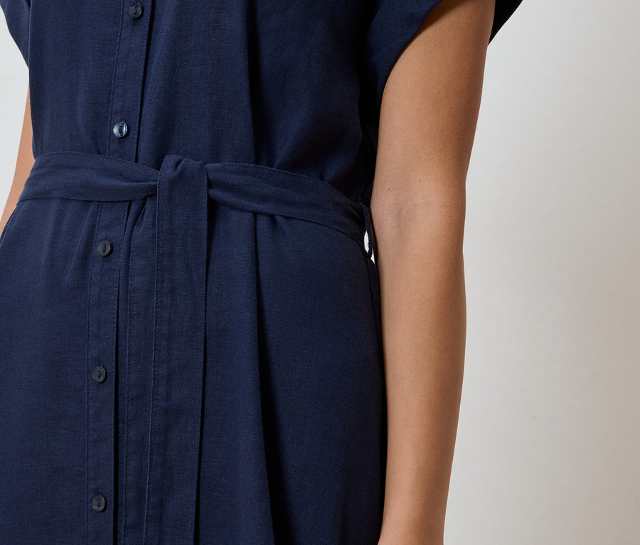 Gros plan d'une robe-chemise bleu marine avec patte de boutonnage et ceinture en tissu.