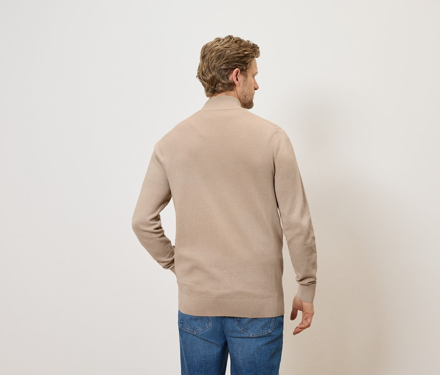 Homme portant un pull en tricot beige et un jean, vu de dos.