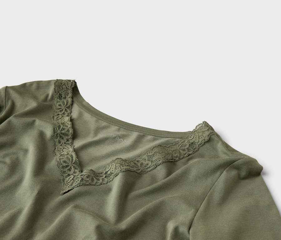 Gros plan sur un haut vert olive avec un col en V et des détails en dentelle.