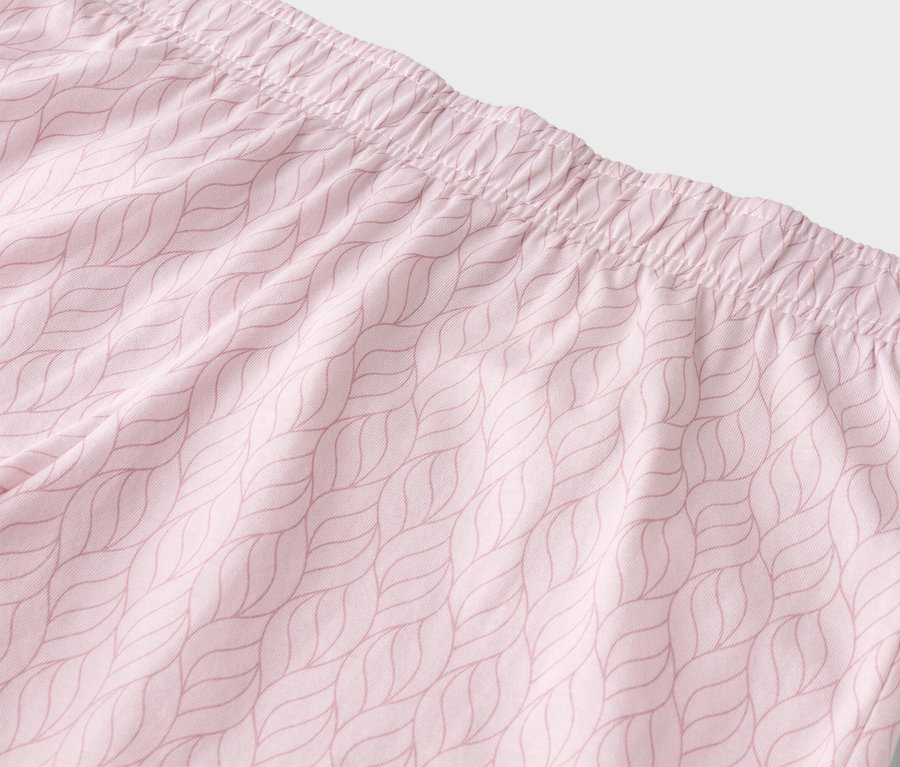 Gros plan de la taille d'un pantalon rose clair avec une ceinture élastique et un motif de feuilles.