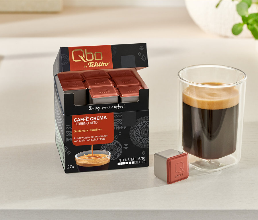 Un verre de café est posé à côté d'une boîte ouverte de capsules Qbo Caffè TERRENO ALTO et d'une capsule individuelle.