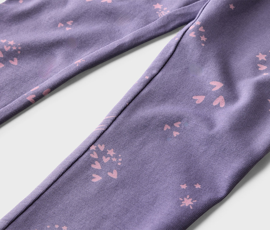 Gros plan d'un pantalon violet avec des motifs roses de cœurs et d'étoiles.