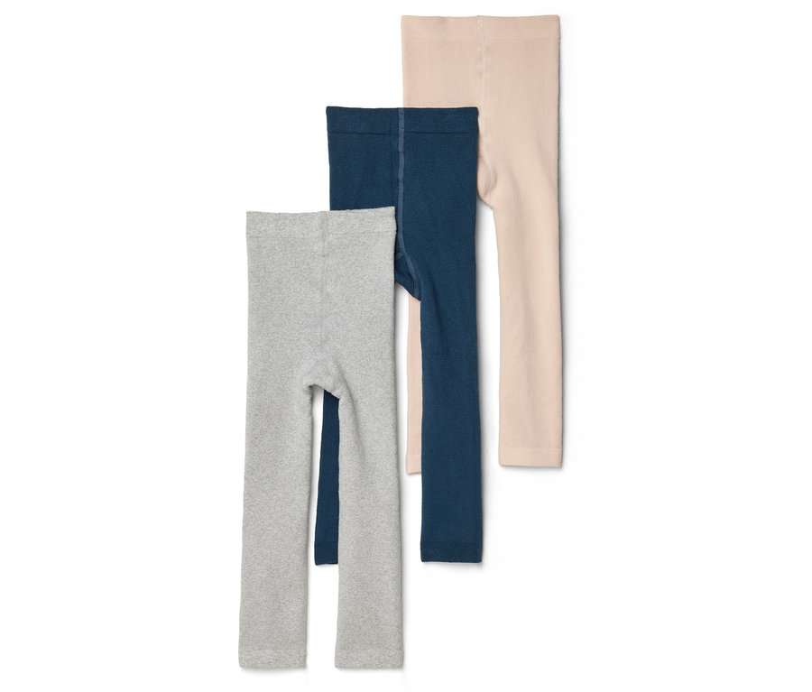 Trois leggings pour enfants en gris, bleu marine et beige sont superposés sur un fond blanc.