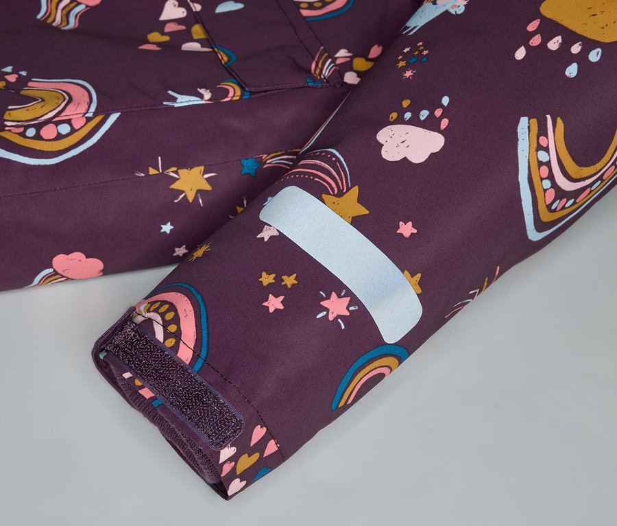 Gros plan sur la manche d'une veste violet foncé avec des motifs arc-en-ciel, étoiles et nuages, et une bande réfléchissante.