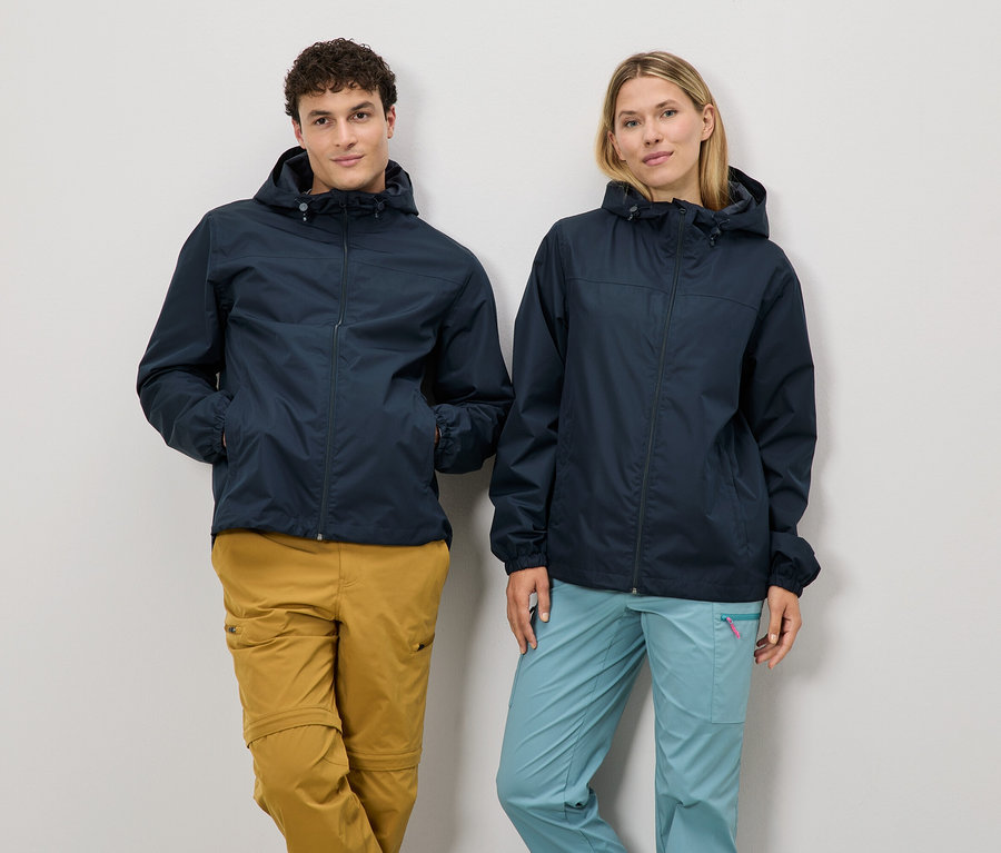 Un homme et une femme se tiennent côte à côte, portant des vestes de pluie bleu marine et des pantalons d'extérieur.