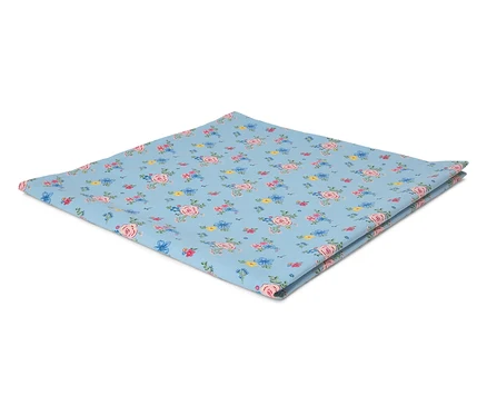 Un tissu carré bleu clair à motifs de roses est posé plié sur une surface blanche.