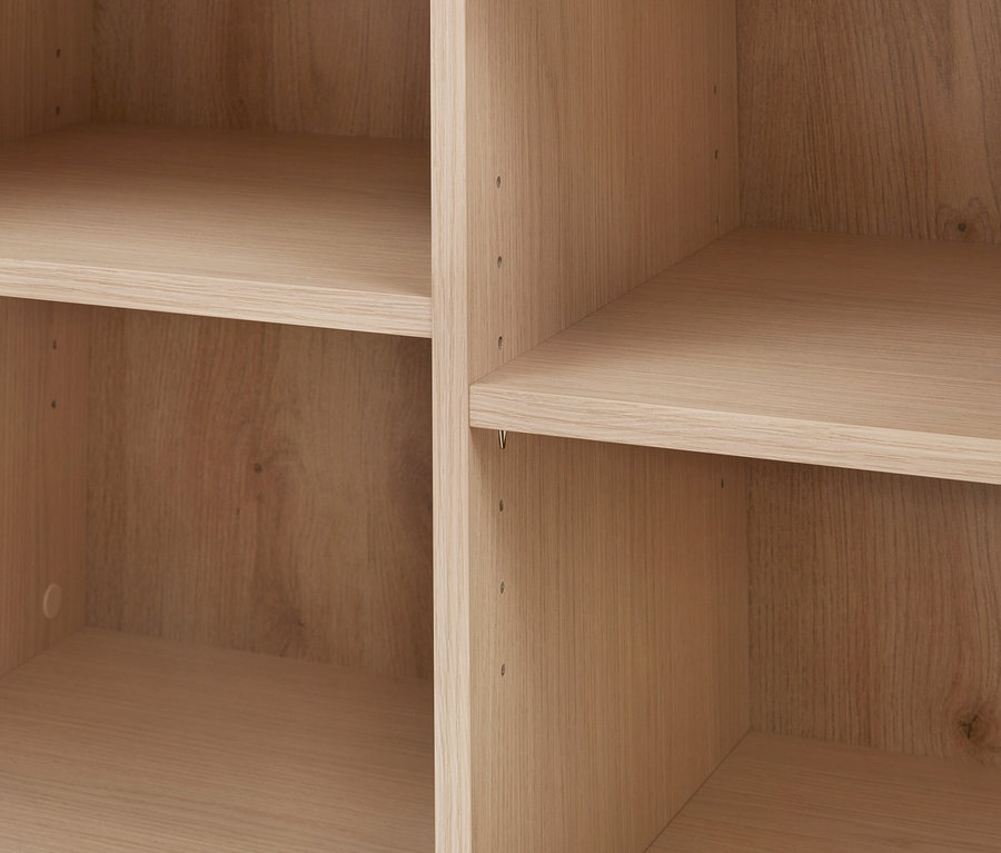 Étagères en bois clair avec grain visible et compartiments vides, avec des trous pour les taquets d'étagère.