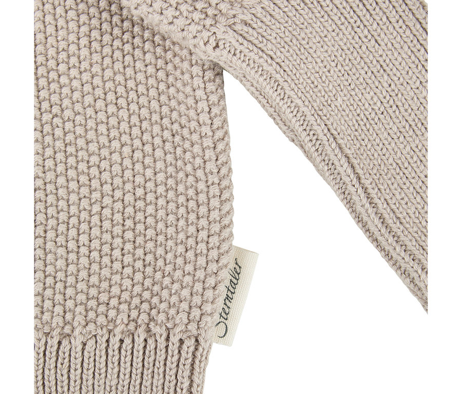 Gros plan d'un gilet bébé Sterntaler beige avec une texture tricotée et une étiquette de marque.