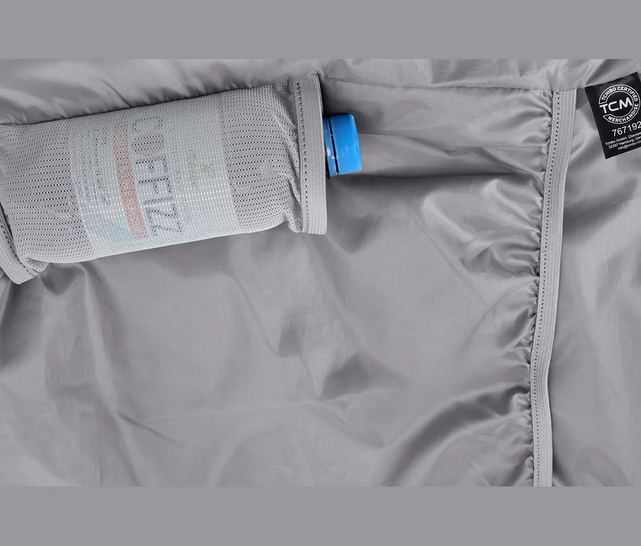 Tissu gris avec une poche en filet contenant une bouteille à bouchon bleu et l'inscription « COFFEEZZ ». Une étiquette TCM est visible à droite.