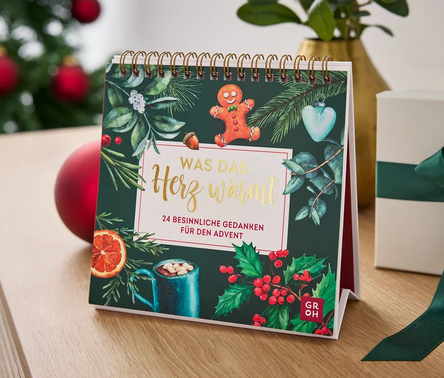 Calendrier de table avec un motif de Noël et une boîte cadeau avec un ruban vert sur une table.