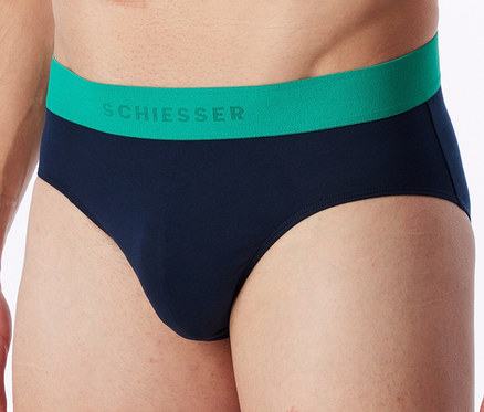 Gros plan d'un homme portant un slip bleu marine avec une ceinture verte sur laquelle est écrit « SCHIESSER ».