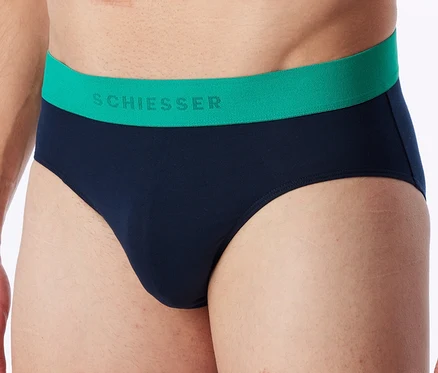 Gros plan d'un homme portant un slip bleu marine avec une ceinture verte sur laquelle est écrit « SCHIESSER ».