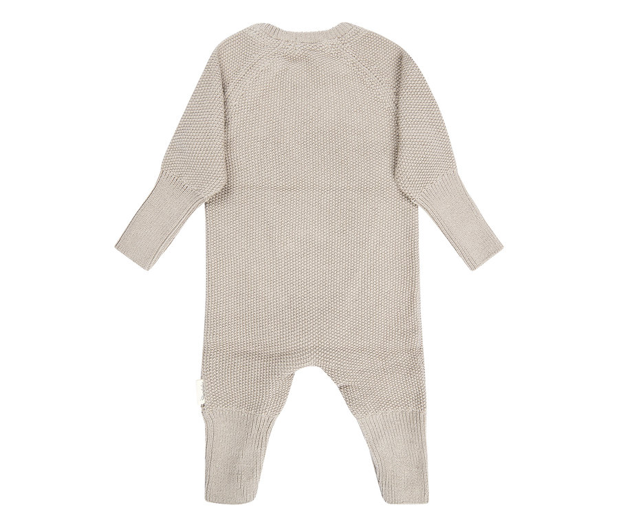 Grenouillère bébé tricotée beige avec manches et jambes longues, poignets et chevilles côtelés.