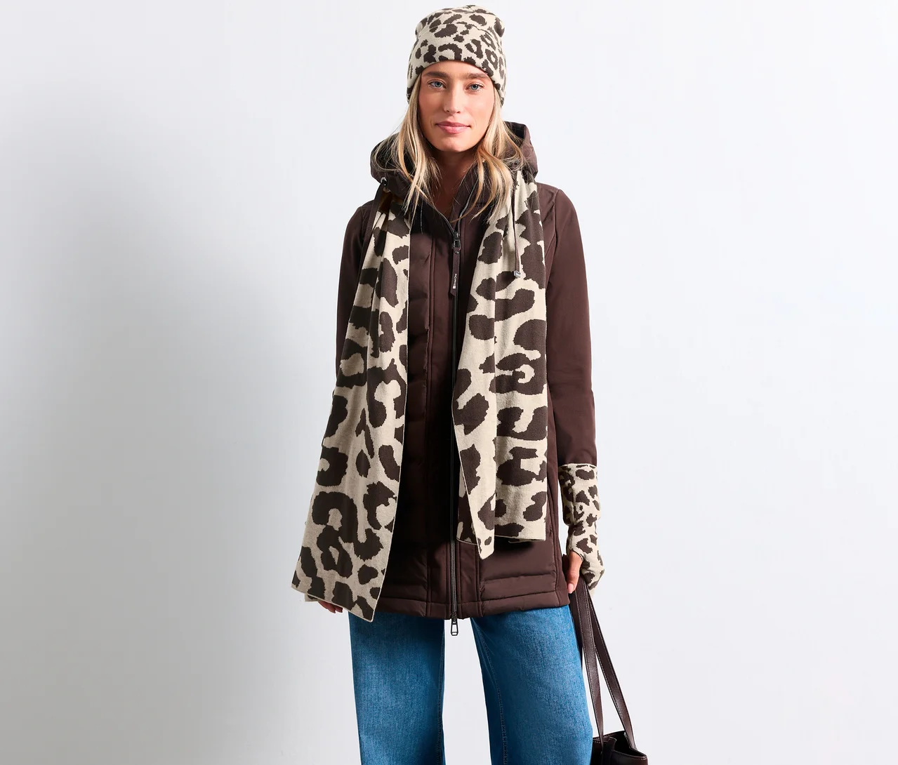 Femme portant une veste marron, un jean bleu, une écharpe en maille fine Street One beige à motif léopard, un bonnet et des mitaines assortis.