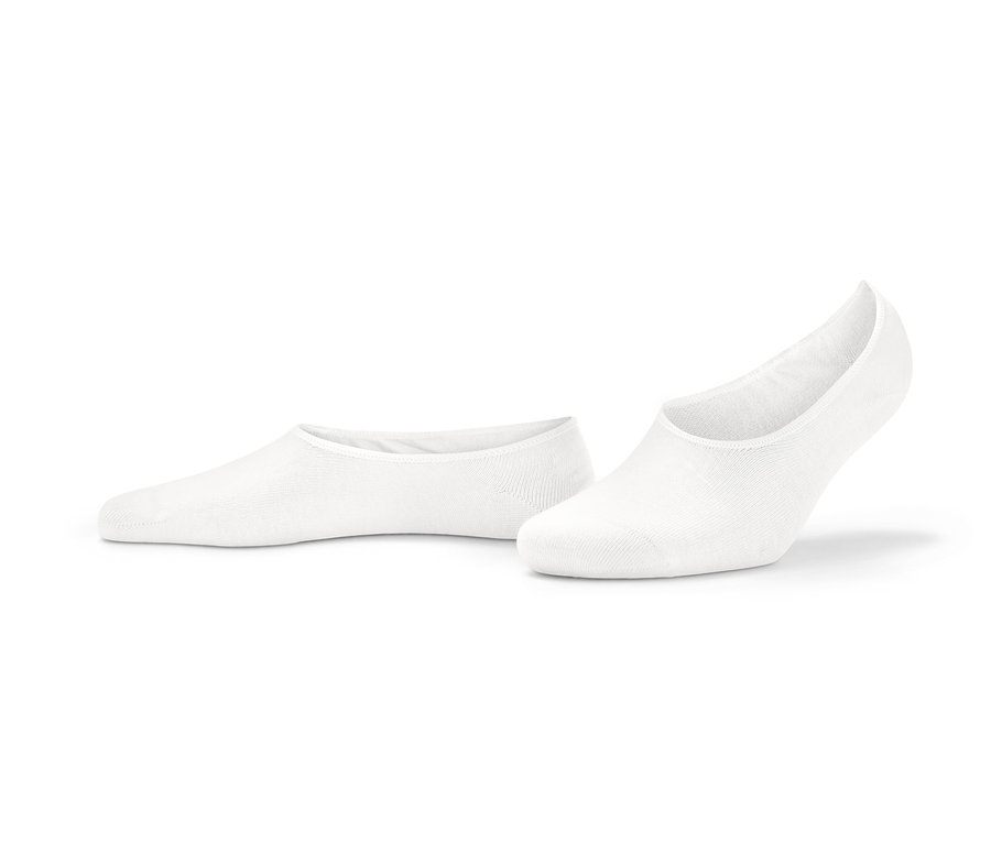 Deux paires de soquettes invisibles blanches pour baskets sont posées sur le sol.