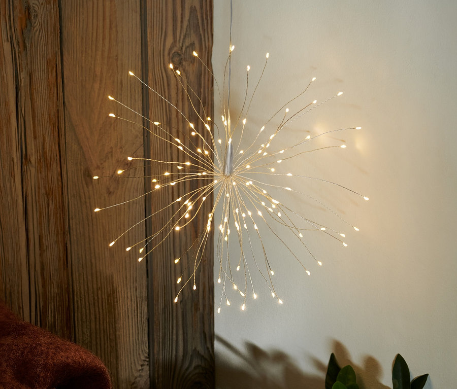 Une branche lumineuse à LED est accrochée au mur, à côté d'une tasse et d'un bol de biscuits.