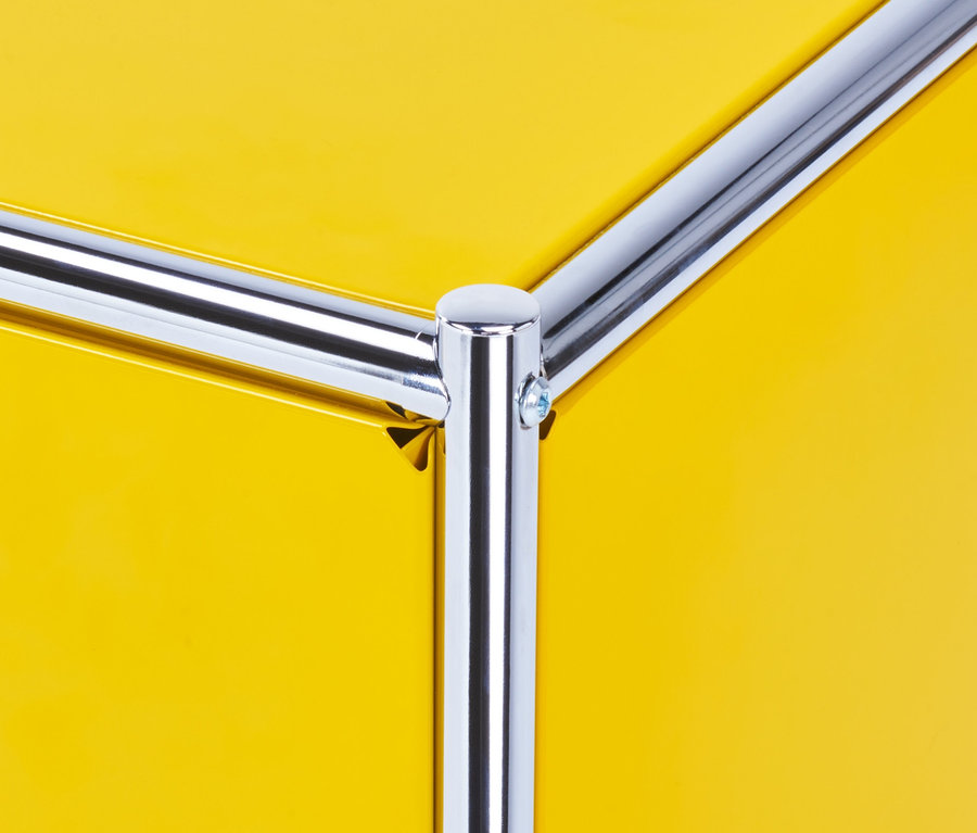 Détail d'un meuble bas en métal jaune « CN3 » avec structure tubulaire chromée.
