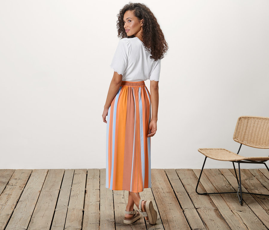 Femme posant en jupe mi-longue à rayures.