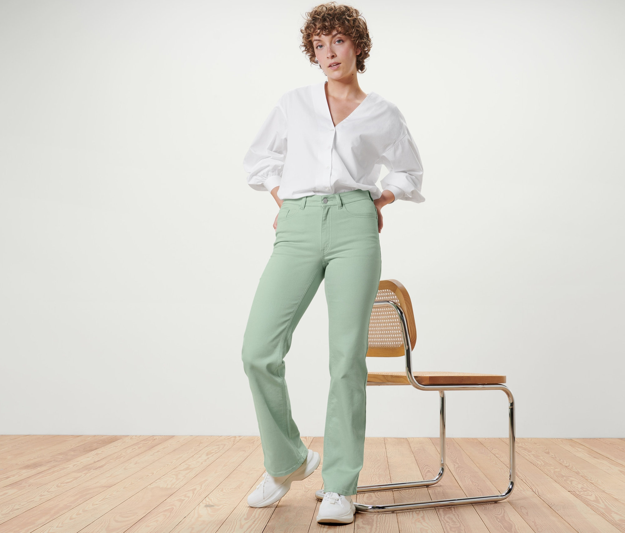 Femme posant en jean bootcut – Fit « Lou », vert menthe, et chemise blanche.
