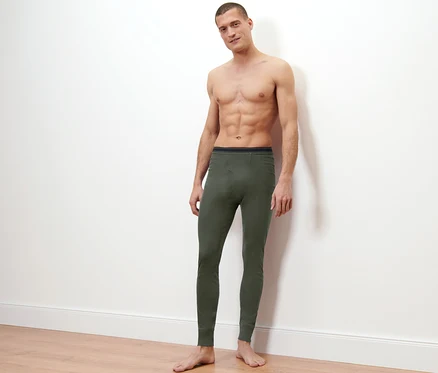 Un homme pose sur un fond clair et porte 2 caleçons longs techniques thermiques.