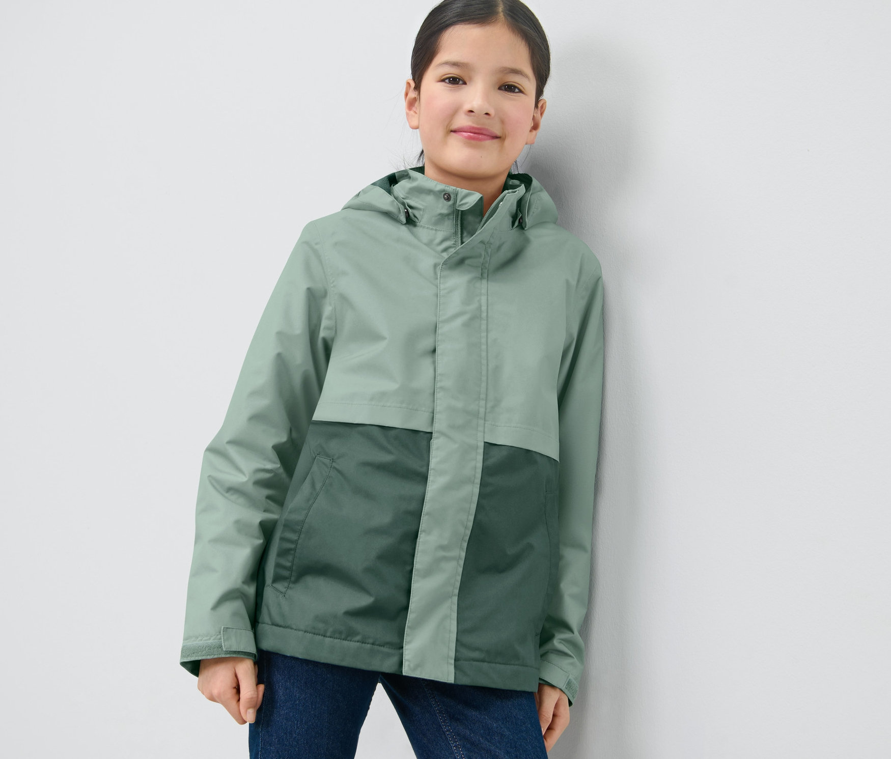 Fille posant dans une veste polyvalente verte pour enfant.