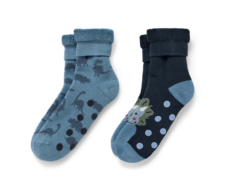 Deux paires de chaussettes antidérapantes pour enfant : une paire bleue avec des dinosaures et des points marron, l’autre bleu foncé avec un motif de dinosaure et des points bleus.