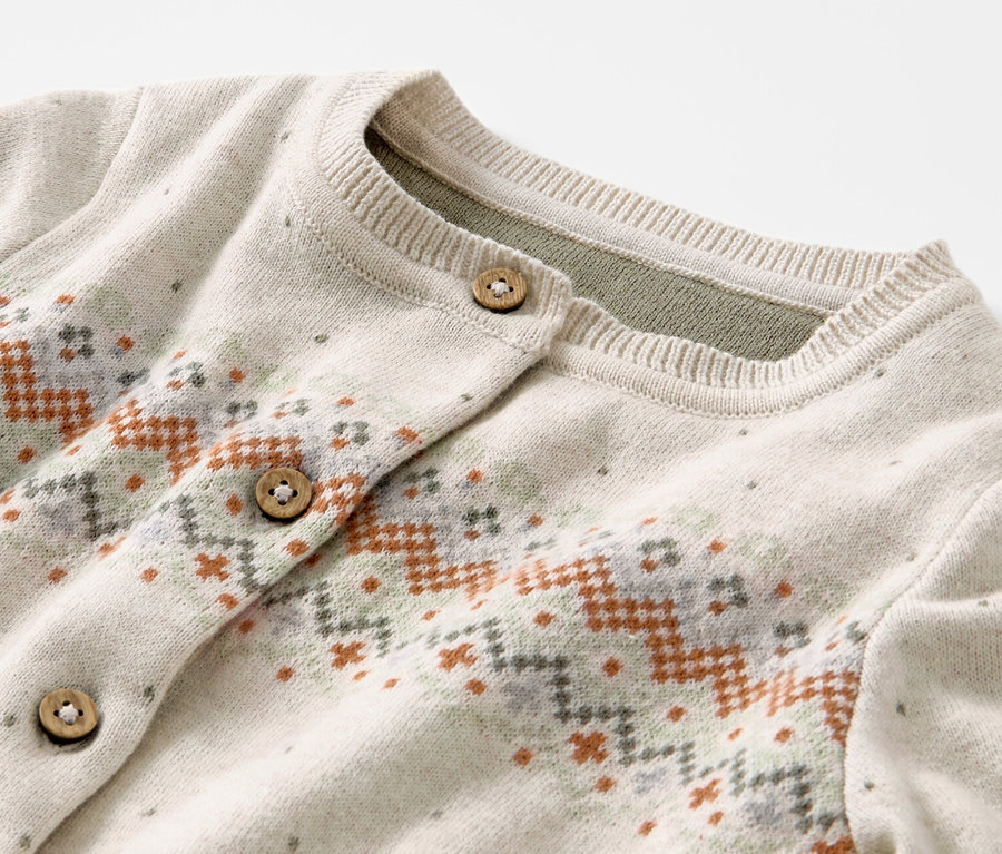 Détail d'un gilet en maille pour enfant avec motif norvégien et boutons en bois.