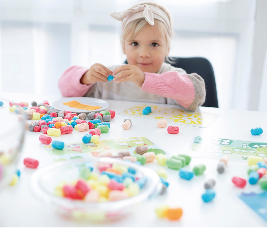 Fille jouant avec un ensemble coloré PlayMais® sur la table.