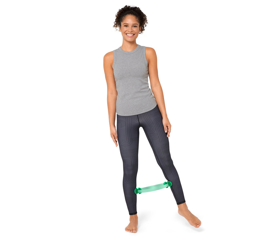 Femme faisant de l'exercice avec un anneau de Pilates entre ses jambes.