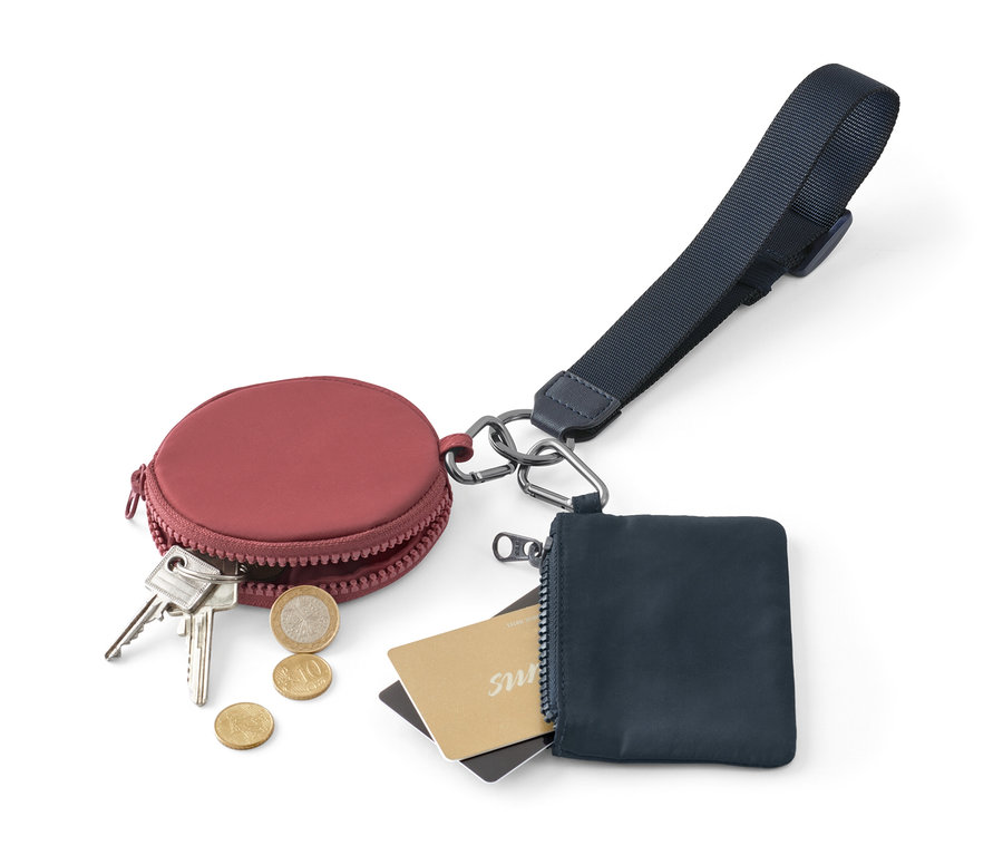 Porte-monnaie rond bordeaux avec clés et pièces à côté d'un porte-monnaie zippé bleu avec cartes et cordon à clés multifonction.