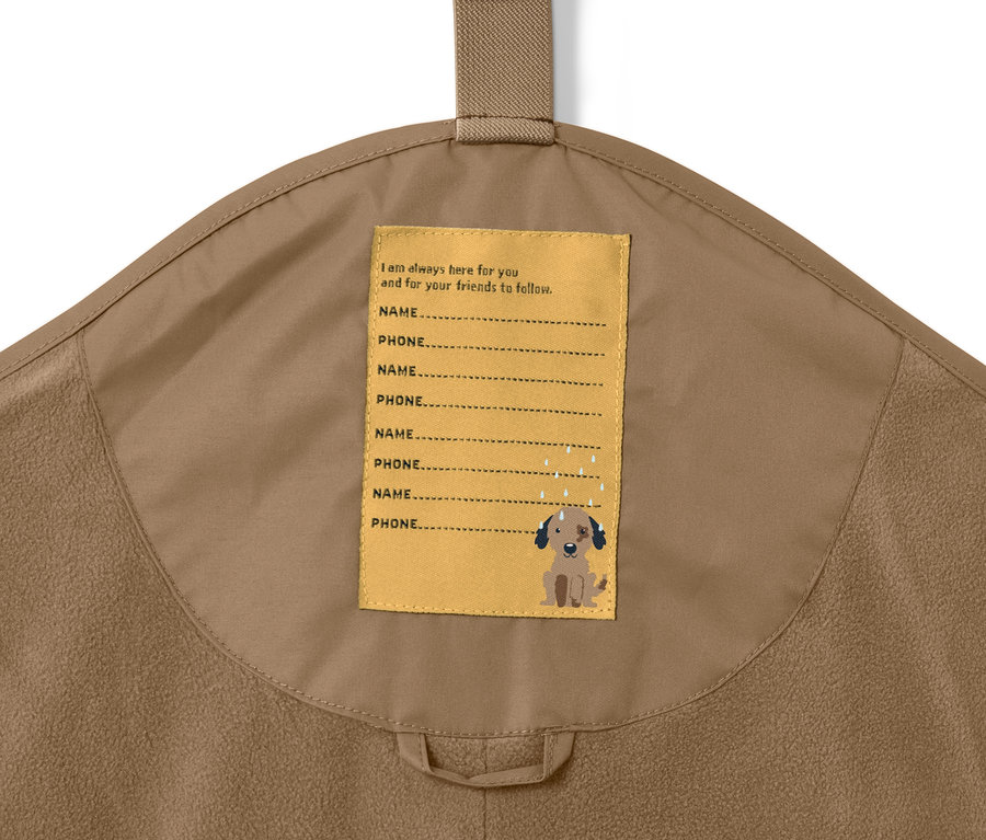 Gros plan sur un pantalon de pluie thermique marron pour enfant avec une étiquette pour le nom et le numéro de téléphone.