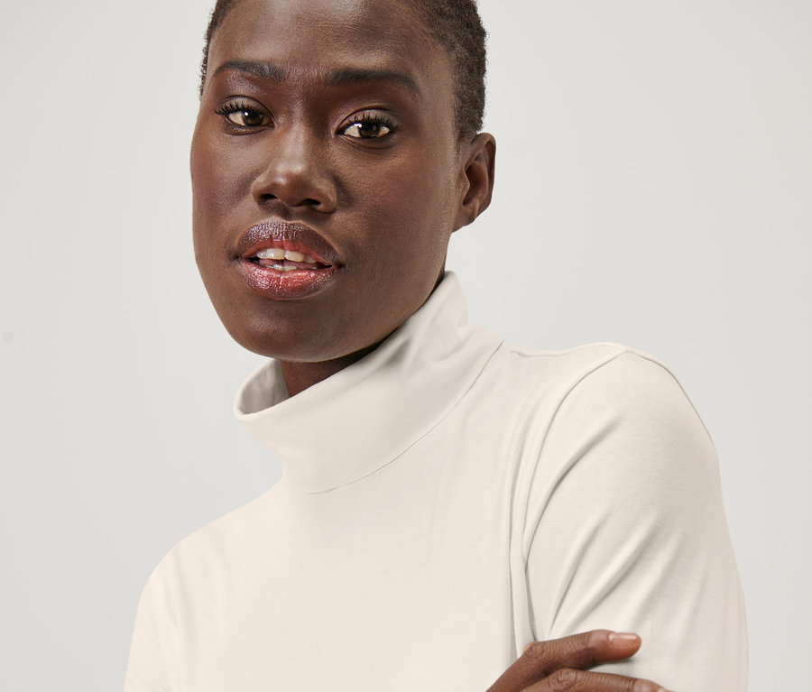 Portrait d'une femme portant un T-shirt col roulé blanc crème.